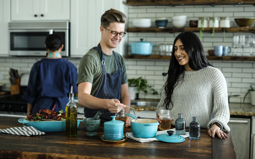 Couple cooking and laughing together in a bright, clean kitchen