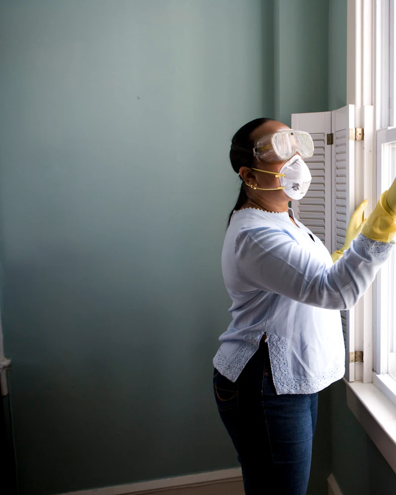 Cleaning professional in gloves carefully wiping a window frame